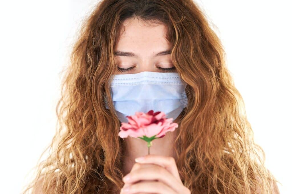 A woman masking her ADHD holds a flower to her masked face